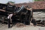Polisi memeriksa kondisi truk bermuatan pakan ternak yang terlibat kecelakaan usai  menabrak sebuah warung makan dan terguling di Jalan Raya Kediri-Kertosono, Purwodadi, Kediri, Jawa Timur, Jumat (24/1/2020). Tidak ada korban jiwa dalam kecelakaan tersebut. Antara Jatim/Ari Bowo Sucipto/zk.