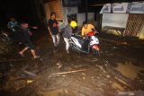 Warga membantu seorang pengendara motor melintas di jalan yang penuh lumpur saat terjadi banjir bandang di Petungsewu, Dau, Malang, Jawa Timur, Jumat (24/1/2020). Banjir bandang akibat meluapnya sungai Loh tersebut mengakibatkan dua orang pengendara motor luka-luka. ANTARA FOTO/HY Prabowo/Abs/zk