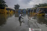 Seorang warga mencari ikan di antara bus sekolah dan Trans Metro Bandung (TMB) yang terendam banjir di Balai Pengujian Kendaraan Dinas Perhubungan, Bandung, Jawa Barat, Sabtu (25/1/2020). Untuk pertama kalinya, pool bus sekolah dan TMB terendam air banjir hingga 80 sentimeter akibat intensitas hujan yang tinggi pada Jumat (24/1) sehingga pelayanan dan aktivitas di pool tersebut terhenti. ANTARA JABAR/Raisan Al Farisi/agr