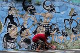 Seorang anak melintas di depan mural penggalan cerita wayang kulit Mahabarata di Kampung Wisata Edukasi Wayang Kulit, Samaan, Malang, Jawa Timur, Minggu (26/1/2020). Hampir seluruh dinding rumah di kampung tersebut dihias dengan mural penggalan cerita wayang kulit Mahabharata dan Ramayana untuk sarana edukasi kepada masyarakat tentang pewayangan sekaligus menghilangkan kesan kumuh. Antara Jatim/Ari Bowo Sucipto/zk