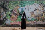 Seorang pengunjung melakukan swafoto di depan mural penggalan cerita wayang kulit Mahabarata di Kampung Wisata Edukasi Wayang Kulit, Samaan, Malang, Jawa Timur, Minggu (26/1/2020). Hampir seluruh dinding rumah di kampung tersebut dihias dengan mural penggalan cerita wayang kulit Mahabharata dan Ramayana untuk sarana edukasi kepada masyarakat tentang pewayangan sekaligus menghilangkan kesan kumuh. Antara Jatim/Ari Bowo Sucipto/zk