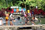 Pengunjung bermain di kolam pemandian di kampung tradisi dan adat (sidat) Jopuro Taman Suruh, Banyuwangi, Jawa Timur, Minggu (26/1/2020). Tempat wisata yang dikelola oleh warga itu, menewarkan wahana pemandian dan pertunjukan kesenian tradisional. Antara Jatim/Budi Candra Setya/zk.