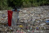 Seorang warga menemukan bendera merah putih di antara sampah plastik di sungai Citepus yang bermuara ke sungai Citarum di Bojong Citepus, Cangkuang Wetan, Dayeuhkolot, Kabupaten Bandung, Jawa Barat, Selasa (28/1/2020). Warga mengatakan sampah tersebut telah satu bulan mengendap dan mereka berharap pemerintah setempat bisa segera membersihkannya karena dapat menimbulkan berbagai penyakit. ANTARA JABAR/Raisan Al Farisi/agr