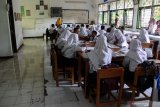 Siswa belajar di ruang kelas yang tergenang air di SMPN 2 Tanggulangin Sidoarjo, Jawa Timur, Selasa (28/1/2020). Banjir yang menggenangi sejak sepekan di kawasan tersebut mengakibatkan sejumlah ruang kelas sekolah masih tergenang air, namun tak menyurutkan semangat siswa untuk tetap belajar. Antara Jatim/Umarul Faruq/zk