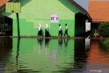 Siswa melintas di area sekolah yang tergenang air di SMPN 2 Tanggulangin Sidoarjo, Jawa Timur, Selasa (28/1/2020). Banjir yang menggenangi sejak sepekan di kawasan tersebut mengakibatkan sejumlah ruang kelas sekolah masih tergenang air, namun tak menyurutkan semangat siswa untuk tetap belajar. Antara Jatim/Umarul Faruq/zk