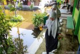 Siswa melintas di area sekolah yang tergenang air di SMPN 2 Tanggulangin Sidoarjo, Jawa Timur, Selasa (28/1/2020). Banjir yang menggenangi sejak sepekan di kawasan tersebut mengakibatkan sejumlah ruang kelas sekolah masih tergenang air, namun tak menyurutkan semangat siswa untuk tetap belajar. Antara Jatim/Umarul Faruq/zk