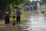 Warga berfoto di tengah banjir yang menggenangi Dusun Beluk, Desa Jombok, Kecamatan Kesamben, Kabupaten Jombang, Jawa Timur, Kamis (6/2/2020). Banjir yang menggenangi 260 rumah di Dusun Beluk sejak lima hari terakhir menjadi lokasi wisata dadakan tak sedikit siswa sekolah luar desa yang malah mandi-mandi di lokasi banjir. Antara Jatim/Syaiful Arif/zk