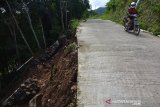 Pengendara melintas di samping tebing yang longsor di Dusun Mligi, Desa Claket, Kecamatan Pacet, Mojokerto, Jawa Timur, Sabtu (8/2/2020). Tebing setinggi 30 meter tersebut longsor pada Jumat (7/2/2020) petang, akibat tidak kuat menahan tingginya curah hujan dan material tanah longsor sempat menutup jalur penghubung Pacet-Trawas. Antara Jatim/Syaiful Arif/zk.