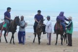 Pemilik kuda tunggangan   melayani pengunjung yang   menggunakan jasanya di Pantai Wisata Lombang,  Sumenep, Jawa Timur, Minggu (9/2/2020). Para penunggang kuda tersebut menawarkan jasanya kepada wisatawan yang ingin naik kuda dengan tarif Rp20 ribu. Antara Jatim/Saiful Bahri/zk