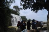 Pengunjung menikmati  Wisata air terjun Toroan, Ketapang, Sampang, Jawa Timur, Minggu (9/2/2020). Air terjun yang  langsung mengalir ke bibir pantai itu menjadi wisata andalan kabupaten setempat. Antara Jatim/Saiful Bahri/zk