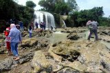 Pengunjung menikmati  Wisata air terjun Toroan, Ketapang, Sampang, Jawa Timur, Minggu (9/2/2020). Air terjun yang langsung mengalir ke bibir pantai itu menjadi wisata andalan kabupaten setempat. Antara Jatim/Saiful Bahri/zk