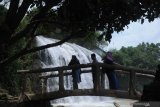 Pengunjung menikmati  Wisata air terjun Toroan, Ketapang, Sampang, Jawa Timur, Minggu (9/2/2020). Air terjun yang  langsung mengalir ke bibir pantai itu menjadi wisata andalan kabupaten setempat. Antara Jatim/Saiful Bahri/zk