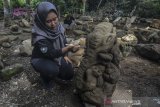 Petugas objek wisata membersihkan patung batu kuno di Desa Linggawangi, Kabupaten Tasikmalaya, Jawa Barat, Selasa (11/2/2020). Sebanyak 22 patung berbentuk seperti manusia kerdil dan satu patung Ganesha atau gajah duduk ditemukan warga di kawasan destinasi wisata Batu Mahpar yang diduga peninggalan sejarah. ANTARA JABAR/Adeng Bustomi/agr