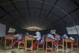 Siswa SD Negeri 3 Cigorowong mengikuti Kegiatan Belajar Mengajar (KBM) di bawah tenda BNPB di Desa Sukamukti, Kecamatan Cisayong, Kabupaten Tasikmalaya, Jawa Barat, Rabu (12/2/2020). Akibat empat ruang kelas mengalami kerusakan hingga ditopang tiang-tiang bambu sejak dua bulan lalu, kini siswa kelas I dan IV terpaksa belajarnya dipindahkan ke tenda darurat meskipun dalam kondisi panas dan kehujanan atas permintaan dari pemerintah daerah. ANTARA JABAR/Adeng Bustomi/agr
