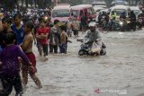 Sejumlah anak mendorong kendaraan yang mogok saat  melintasi genangan air di kawasan Cikadut, Bandung, Jawa Barat, Minggu (16/2/2020). Genangan air setinggi 40-60 cm tersebut terjadi saat intensitas curah hujan yang tinggi akibat drainase buruk yang juga menyebabkan terjadinya kemacetan lalu lintas.  ANTARA JABAR/Novrian Arbi/agr