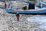 Warga melintas diantara tumpukan sampah di Pantai Sampangan Muncar, Banyuwangi, Jawa Timur, Kamis (20/2/2020). Menurut warga setempat, tumpukan sampah yang menutupi pasir disepanjang pesisir pantai itu, selain dampak banjir besar sungai Wagut pada 2014 juga karena kebiasaan buruk masyarakat yang membuang sampah sembarangan di Pantai. Antara Jatim/Budi Candra Setya/zk