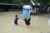 Warga melintasi banjir di Desa Laden, Pamekasan, Jawa Timur, Minggu (23/2/2020). Hujan deras selama hampir enam jam pada hari Sabtu (22/2) menyebabkan sungai yang membelah kota kabupaten tersebut, meluap dan menggenangi ratusan pemukiman warga dengan ketinggian air hingga 160 cm. Antara Jatim/Saiful Bahri/zk