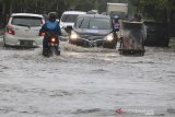 Warga melintasi genangan air di jalan Yos Sudarso, Indramayu, Jawa Barat, Senin (24/2/2020). Genangan air setinggi 40cm-60cm tersebut akibat intensitas hujan yang tinggi serta buruknya sistem drainase sehingga sejumlah jalan protokol di Indramayu. ANTARA JABAR/Dedhez Anggara/agr