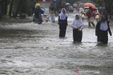 Warga melintasi genangan air di jalan Yos Sudarso, Indramayu, Jawa Barat, Senin (24/2/2020). Genangan air setinggi 40cm-60cm tersebut akibat intensitas hujan yang tinggi serta buruknya sistem drainase sehingga sejumlah jalan protokol di Indramayu. ANTARA JABAR/Dedhez Anggara/agr