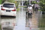 Warga melintasi banjir yang menggenang di perumahan Artha Graha, Sindang, Indramayu, Jawa Barat, Rabu (26/2/2020). Banjir akibat hujan deras yang terjadi pada Minggu (23/2) lalu masih merendam puluhan rumah di daerah tersebut. ANTARA JABAR/Dedhez Anggara/agr