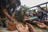 Warga berebut buah kurma usai dipanen di halaman masjid Agung, Kota Tasikmalaya, Jawa Barat, Rabu (26/2/2020). Sebanyak lima pohon kurma yang tumbuh di halaman masjid diantaranya dua pohon berbuah pertama dan sempat viral di media sosial itu dipanen serta dibagikan kepada jamaah. ANTARA JABAR/Adeng Bustomi/agr