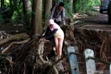 Warga menyeberang di jembatan yang ambrol diterjang banjir di Desa Alas Buluh, Wongsorejo, Banyuwangi, Jawa Timur, Kamis (5/3/2020). Hujan deras yang mengguyur daerah hulu di daerah itu, mengakibatkan jembatan putus serta puluhan hektar lahan pertanian cabai rusak. Antara Jatim/Budi Candra Setya/zk.