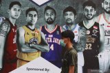 Seorang penonton yang mengenakan masker melintas di depan baliho Indonesia Basketball League (IBL) 2020 Seri VII di GOR Bimasakti, Malang, Jawa Timur, Jumat (13/3/2020). Operator liga basket nasional memutuskan untuk membatalkan penyelenggaraan kompetisi IBL 2020 Seri VII guna meminimalisasi penyebaran virus corona di Indonesia. Antara Jatim/Ari Bowo Sucipto/zk.