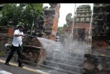 Petugas menyemprotkan cairan disinfektan di kawasan Jalan Gajah Mada, Denpasar, Bali, Rabu (18/3/2020). Penyemprotan disinfektan di sejumlah ruas jalan protokol di Denpasar tersebut dilakukan sebagai upaya untuk mencegah penyebaran COVID-19. ANTARA FOTO/Fikri Yusuf/nym.
