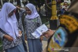 Petugas Satpol PP memeriksa identitas pelajar yang terjaring razia di taman kota Tasikmalaya, Jawa Barat, Rabu (18/3/2020). Razia tersebut dilakukan untuk mengantisipasi pelajar yang melakukan aktivitas di ruang publik agar mengikuti proses belajar dengan sistem daring di rumah sebagai antisipasi pencegahan COVID-19. ANTARA JABAR/Adeng Bustomi/agr