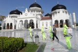 Personil kepolisian Polda Aceh dari jajaran Polresta Banda Aceh, Satuan Brimob dan Bid Dokkes melakukan penyemprotan cairan desinfektan di Masjid Raya Baiturrahman, Banda Aceh, Aceh, Jumat (20/3/2020). Penyemprotan disinfektan yang dilakukan sebelum pelaksanaan ibadah salat jumat itu guna mencegah penularan virus Corona 2019 (COVID-19). Antara Aceh/Irwansyah Putra.