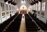 Petugas keamanan gereja melintas diantara kursi kosong di Gereja Katedral Surabaya, Jawa Timur, Minggu (22/3/2020). Keuskupan Surabaya memutuskan meniadakan misa atau pun semua kegiatan yang melibatkan banyak umat Katolik untuk mengantisipasi persebaran virus corona (COVID-19).  Antara Jatim/Zabur Karuru