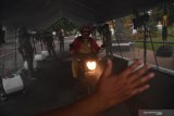 Petugas Satpol PP Jatim memberikan arahan kepada pengendara ketika memasuki bilik penyemprotan disinfektan untuk kendaraan di Gedung Grahadi di Surabaya, Jawa Timur, Senin (23/3/2020). Bilik tersebut wajib dilewati setiap kendaraan yang masuk guna mengantisipasi penyebaran Virus Corona (COVID-19). Antara Jatim/Zabur Karuru