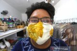 Pengurus yayasan menggunakan masker sasirangan berbahan pewarna alami yang ramah lingkungan buatan penyandang disabilitas di Showroom Yayasan Rumah Kreatif dan Pintar di Banjarmasin, Kalimantan Selatan, Rabu (25/3/2020). Masker buatan penyandang disabilitas tersebut untuk di bagikan gratis kepada ojek online, petugas kebersihan serta masyarakat yang sangat memerlukan sebagai bentuk kepedulian dalam upaya mencegah penyebaran virus corona (COVID-19). Foto Antaranews Kalsel/Bayu Pratama S.