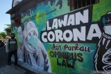 Warga melintas di depan mural Lawan Corona di Jalan Wonokromo, Surabaya, Jawa Timur, Kamis (26/3/2020). Mural karya Serikat Mural Surabaya tersebut merupakan media edukasi kepada warga agar mencegah potensi penyebaran virus corona atau COVID-19, salah satunya dengan cara memakai masker saat beraktivitas di luar rumah. Antara Jatim/Moch Asim/zk.