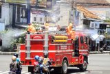 Petugas Dinas Pemadam Kebakaran Sidoarjo menyemprotkan larutan disinfektan di sepanjang jalan kawasan Sidoarjo, Jawa Timur, Kamis (26/3/2020). Penyemprotan menggunakan mobil pemadam kebakaran tersebut bertujuan untuk mengantisipasi penyebaran Virus Corona (COVID-19). Antara Jatim/Umarul Faruq/zk