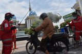 Petugas Palang Merah Indonesia (PMI) Kota Madiun menyemprotkan cairan disinfektan pada umat muslim yang akan melaksanakan Ibadah shalat Jumat di Masjid Agung Baitul Hakim, Kota Madiun, Jawa Timur, Jumat (27/3/2020). Penyemprotan tersebut dimaksudkan untu pencegahan penyebaran COVID-19 atau virus Corona. Antara Jatim/Siswowidodo/zk.