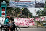 Warga melintas di dekat akses masuk kampung yang ditutup di kawasan Pakem, Sleman, D.I Yogyakarta, Jumat (27/3/20). Sejumlah kampung di Kecamatan Pakem, Sleman menutup sejumlah akses masuk kampung dengan bambu yang diberi tulisan 