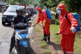 Petugas BPBD menyemprotkan cairan desinfektan ke sejumlah kendaraan di Jalan Lintas Blitar-Malang di Blitar, Jawa Timur, Sabtu (28/3/2020). Selain melakukan penyekatan dan pembatasan kendaraan yang hendak keluar-masuk, Petugas Gabungan dari Gugus Tugas Percepatan Penanganan Virus Corona (COVID-19) Kabupaten Blitar juga melarang sejumlah kendaraan dari daerah lain yang tidak memiliki kepentingan untuk memasuki kawasan Blitar, Guna menekan penyebaran COVID-19. Antara Jatim/Irfan Anshori/zk