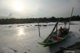 Nelayan beraktivitas di sekitar muara sungai Tambak Wedi yang dipenuhi limbah busa putih di Surabaya, Jawa Timur, Minggu (29/3/2020). Limbah busa putih itu hanyut hingga ke Selat Madura. Antara Jatim/Didik/Zk