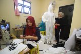 Pelaku UMKM V-RA Collection, Novita Rahayu Purwaningsih (kiri) menyelesaikan pembuatan baju alat pelindung diri (APD) di Surabaya, Jawa Timur, Minggu (29/3/2020). Dinas Perdagangan Kota Surabaya mengerahkan sekitar 20 UMKM untuk membuat baju APD berbahan kain gore-tex yang akan didistribusikan oleh Dinas Kesehatan ke seluruh rumah sakit yang membutuhkan dalam menangani pandemi COVID-19. Antara Jatim/Moch Asim/zk.