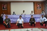 Ketua Forum Komunikasi Badan Usaha Milik Negara (FK BUMN) Aceh, Ferry Heriawan (kedua kanan belakang) bersama Kepala Dinas Sosial Aceh, Alhudri (tengah belakang) dan perwakilan jajaran BUMN Aceh memegang spanduk saat penyerahan bantuan sembako di Banda Aceh, Aceh, Selasa (31/3/2020). FK BUMN Aceh tahap awal menyerahkan sebanyak 1.057 paket sembako  dari total target sebanyak 3.000 paket sembako melalui Dinas Sosial Aceh untuk pekerja informal dan warga prasejahtera  yang terdampak virus COVID-19. Antara Aceh/Ampelsa.