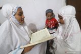 Seorang ibu bersama dua anaknya membaca Al-Quran di rumahnya di Kota Kediri, Jawa Timur, Senin (30/3/2020). Pemerintah menghimbau masyarakat untuk berada di dalam rumah dan menghindari aktivitas di tempat publik sebagai upaya mencegah penyebaran COVID-19. Antara Jatim/Prasetia Fauzani/zk.