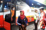 Petugas kepolisian menyemprotkan cairan disinfektan kepada penumpang saat tiba di kedatangan terminal Bungurasih, Sidoarjo, Jawa Timur, Selasa (31/3/2020). Sosialisasi dan penyemprotan cairan disinfektan secara massal di jalanan protokol dan fasilitas umum tersebut bertujuan untuk mencegah penyebaran virus corona baru atau COVID-19. Antara Jatim/Umarul Faruq/zk