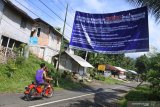 Warga melintas di bawah poster penolakan tempat karantina di objek Wisata Rembangan Desa Kemuning Lor, Arjasa, Jember, Jawa Timur, Selasa (31/3/2020). Warga Desa Kemuning Lor menolak dijadikannya Hotel Rembangan di lokasi wisata tersebut sebagai tempat karantina orang dalam pemantauan (ODP) Covid-19 karena tempat itu bersuhu dingin, berada di ketinggian dan dikhawatirkan limbah medisnya mencemari air. Antara Jatim/Seno/zk