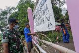 Warga menutup salah satu pintu masuk di Desa Sampih, Wonopringgo, Kabupaten Pekalongan, Jawa Tengah, Senin (30/3/20). Sejumlah desa di Kabupaten Pekalongan mulai memberlakukan akses satu pintu masuk utama dan menutup pintu lainnya serta mewajibkan warga yang datang di cek suhu badan serta disemprot cairan disinfektan untuk mencegah menyebarnya virus Corona (COVID-19). ANTARA FOTO/Harviyan Perdana Putra/aww.