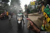 Suporter sepak bola membagikan nasi bungkus kepada pengemudi ojek daring di Jalan Bubutan, Surabaya, Jawa Timur, Jumat (3/4/2020). Kegiatan imbauan menghindari keramaian, penyemprotan disinfektan serta pemberian nasi bungkus yang dilakukan oleh pihak kepolisian bersama suporter sepak bola tersebut untuk mencegah penyebaran Virus Corona (COVID-19) dan meringankan beban ekonomi para pengemudi ojek daring. Antara Jatim/Didik/Zk