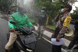 Polisi memberikan imbauan dan penyemprotan kepada pengemudi ojek daring di Jalan Bubutan, Surabaya, Jawa Timur, Jumat (3/4/2020). Kegiatan imbauan menghindari keramaian, penyemprotan disinfektan serta pemberian nasi bungkus yang dilakukan oleh pihak kepolisian bersama suporter sepak bola tersebut untuk mencegah penyebaran Virus Corona (COVID-19) dan meringankan beban ekonomi para pengemudi ojek daring. Antara Jatim/Didik/Zk