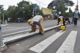 Pekerja memasang portal menggunakan besi guardrail di sebuah perempatan jalan di Kota Madiun, Jawa Timur, Kamis (2/4/2020). Pemkot Madiun membatasi mobilitas warga antara lain dengan memasang sejumlah portal dan barier di beberapa lokasi guna mencegah penyebaran COVID-19 atau virus corona. Antara Jatim/Siswowidodo/zk.