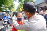 Kapolres Tulungagung AKBP Eva Guna Pandia (kanan) memasangkan masker gratis untuk pengendara motor yang melintas di jalan raya Kota Tulungagung, Jawa Timur, Jumat (3/4/2020). Sebanyak 20 ribu masker gratis produksi UKM lokal dibagikan jajaran kepolisian setempat kepada ribuan anggota Polri dan Bhayangkara guna meminimalkan risiko penularan virus corona atau COVID-19 di daerah itu. Antara Jatim/Destyan Sujarwoko/zk.