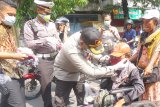 Petugas membagikan masker gratis untuk pengendara motor yang melintas di jalan raya Kota Tulungagung, Jawa Timur, Jumat (3/4/2020). Sebanyak 20 ribu masker gratis produksi UKM lokal dibagikan jajaran kepolisian setempat kepada ribuan anggota Polri dan Bhayangkara guna meminimalkan risiko penularan virus corona atau COVID-19 di daerah itu. Antara Jatim/Destyan Sujarwoko/zk.